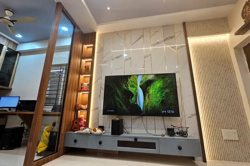 A marble TV wall beside a study, divided by a lit glass screen.