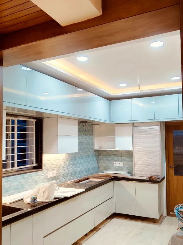 An L-shaped kitchen in white, with mosaic tiles.